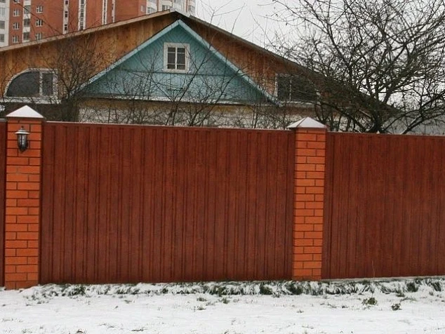 Красивый забор для частного дома из профлиста под дерево с кирпичными столбами